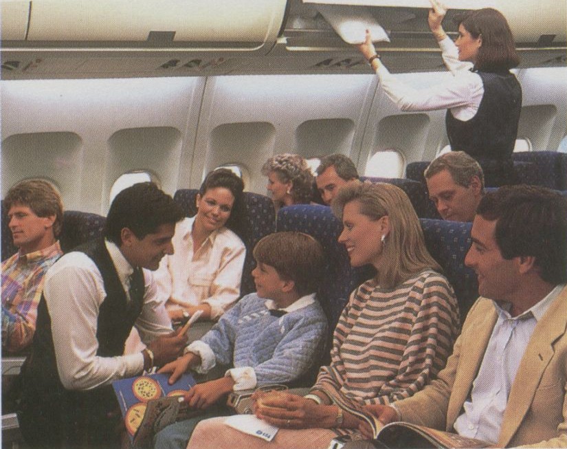 1990s Pan Am Flight Attendants assist customers in the economy cabin of an Airbus A310